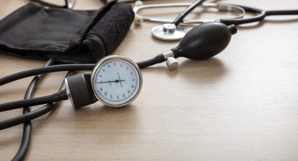 A blood pressure monitor with stethoscope on a wooden table.