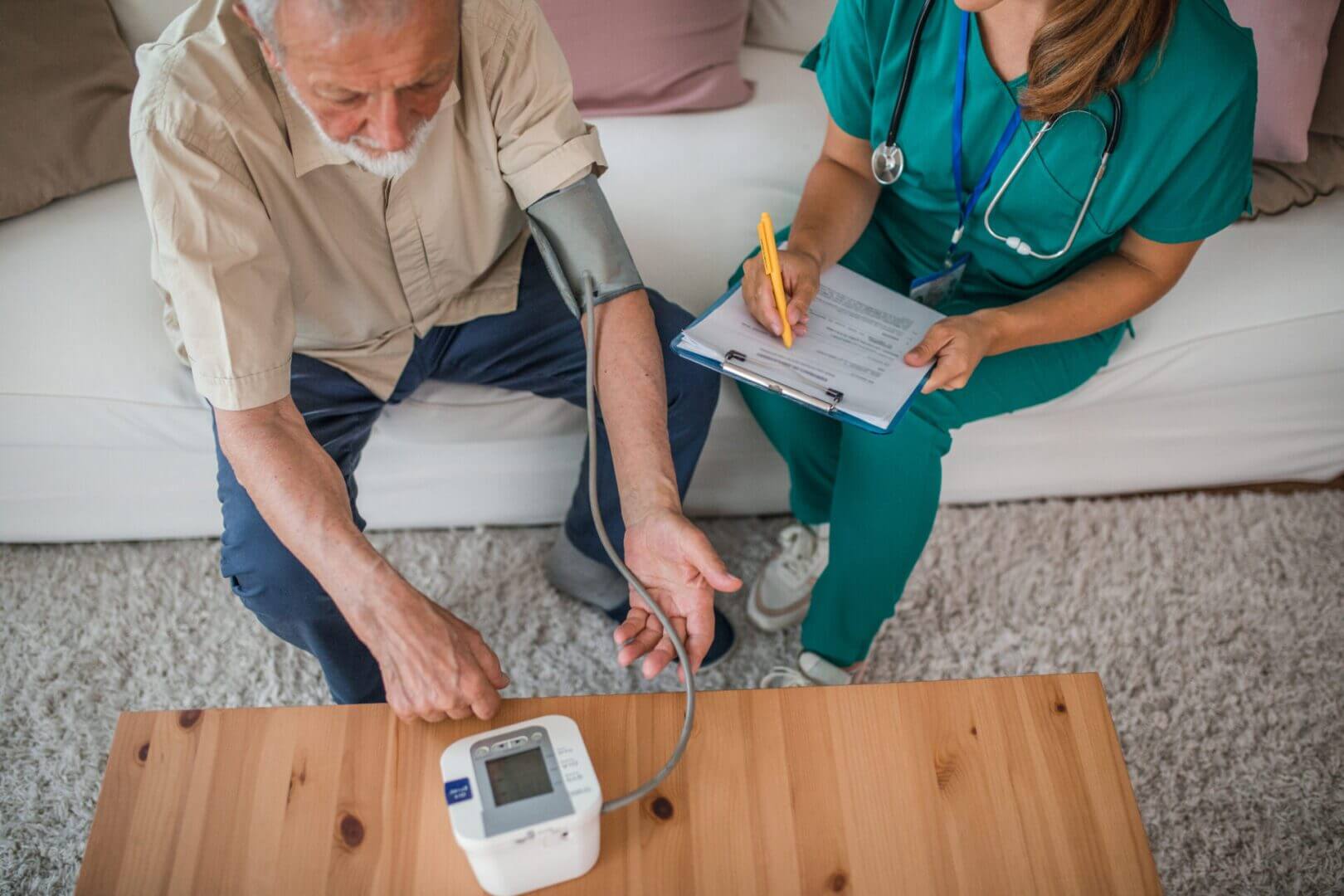 A nurse measuring an elderly man's blood pressure at home.